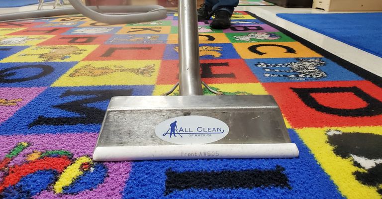 Steam cleaning wand refreshing a colorful alphabet classroom rug.
