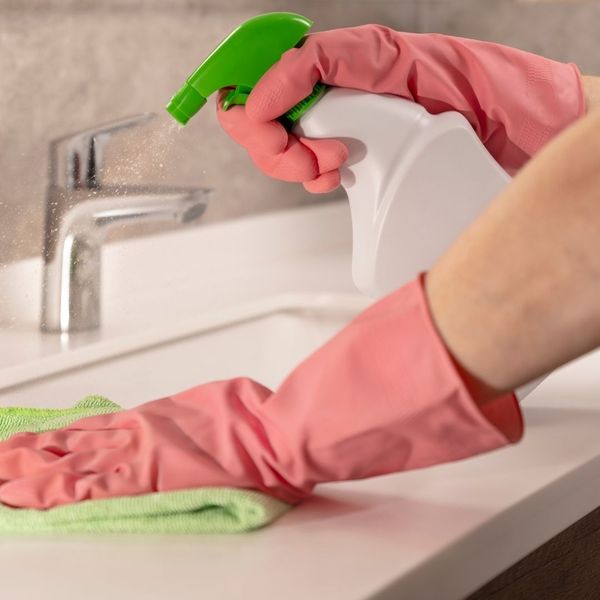 A gloved hand wiping off a bathroom counter.