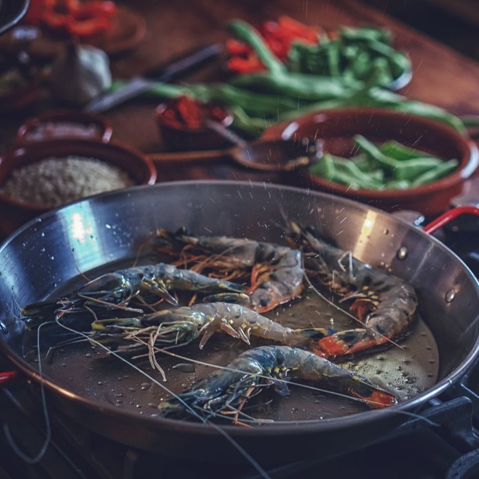 fresh shrimp cooking in a skillet with peppers in the background