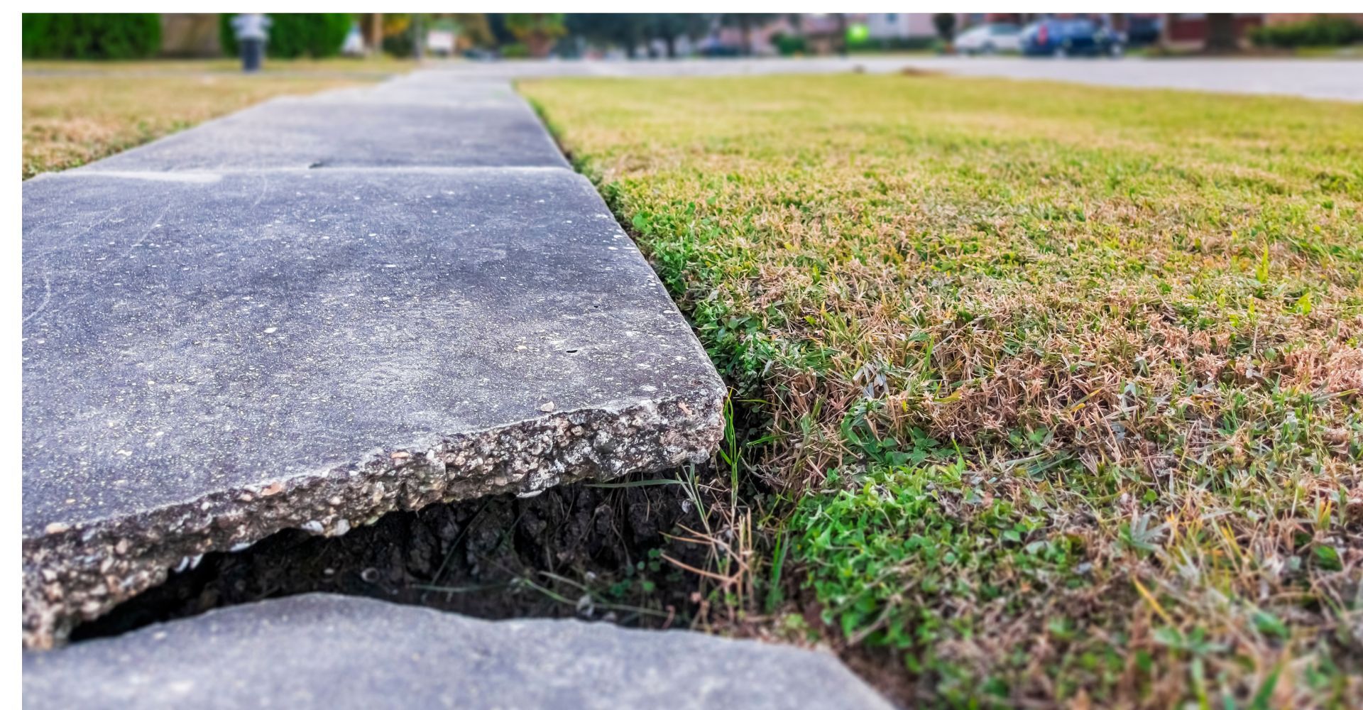 Large crack in uneven concrete sidewalk