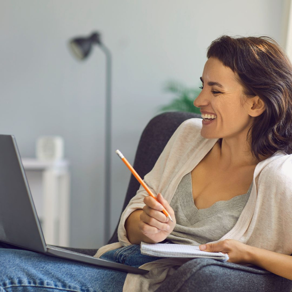 woman on a virtual call, smiling and taking notes. woman on a virtual call, smiling and taking notes.