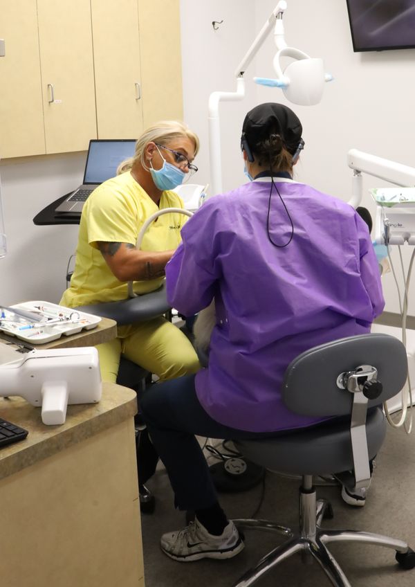 dentist and dental assistant work on a persons teet