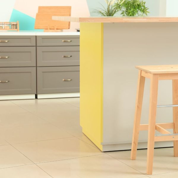 A bright yellow island counter surrounded by grey cabinets