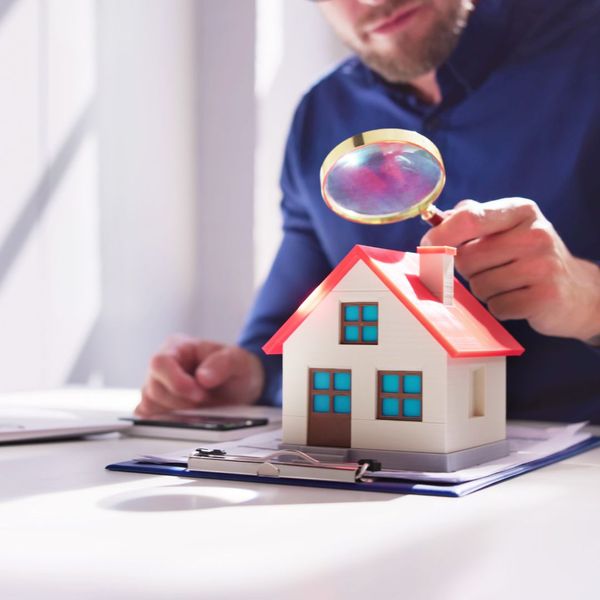 Person with magnifying glass and house