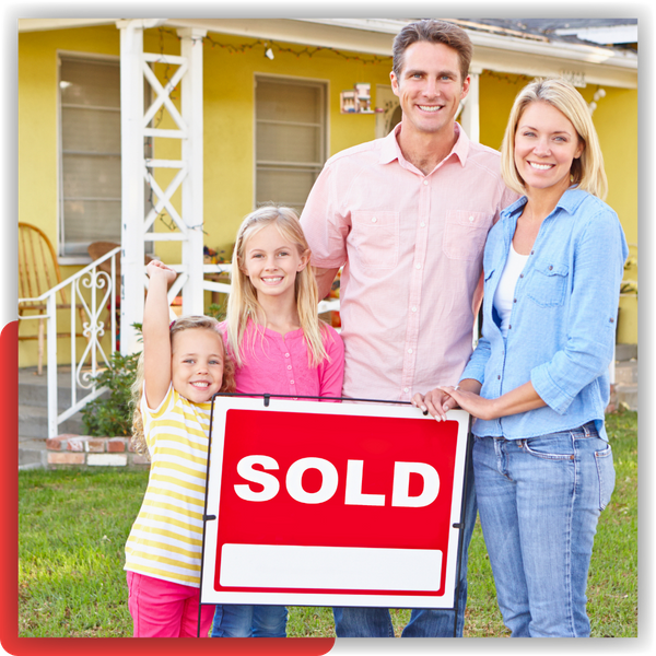 Family in front of a house around a sold sign 