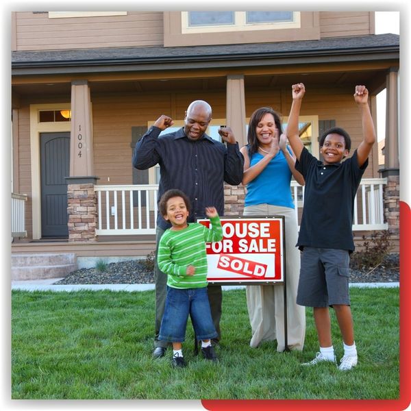 happy family standing by SOLD sign in front of home