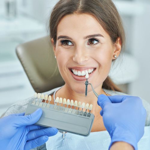 dentist finding color for woman's teeth whitening service
