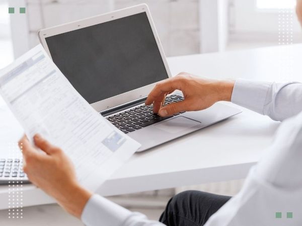 typing on laptop with paperwork