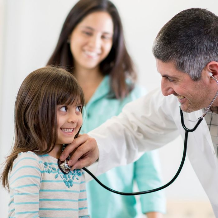 male doctor using a stethoscope to check a young girl's heart