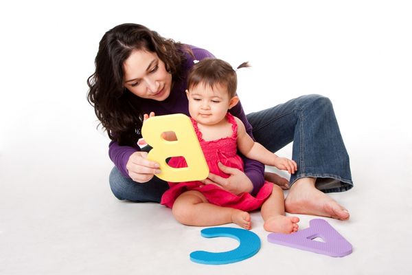 Infant caregiver teaching a baby the alphabet.