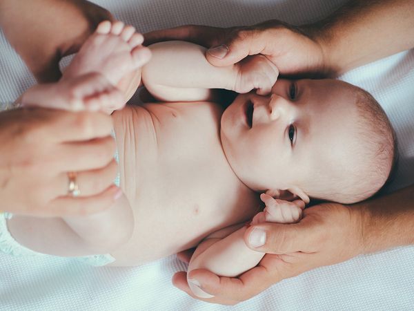 Baby with adults holding their arms and legs