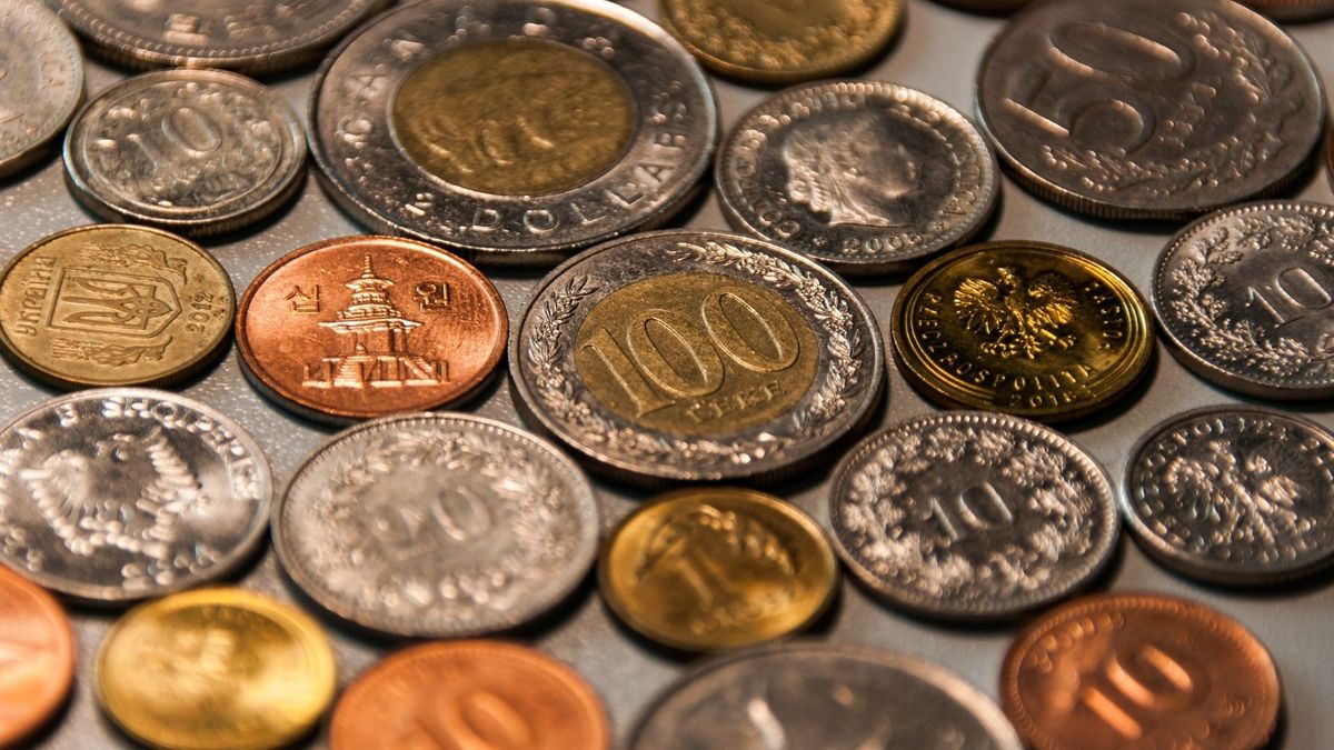 A wide-angle, shallow-depth-of-field photograph of various international coins scattered on a flat surface.