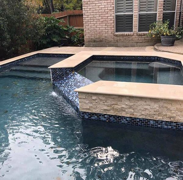 Sheer descent water wall above a fresh waterline tile band on a Houston pool