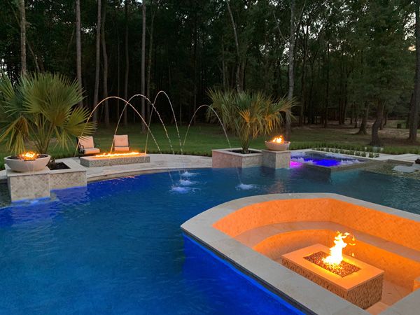 Houston pool and spa lit at night with LED lighting and lit fire bowls