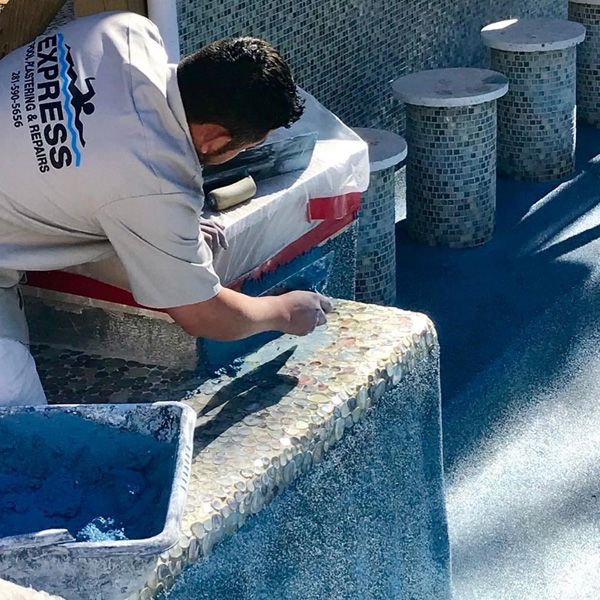 Express Pool Plastering crew member finishing the raised tile wall of a Houston pool