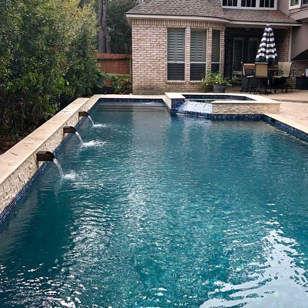 Houston pool and spa with a spillway behind a brick home