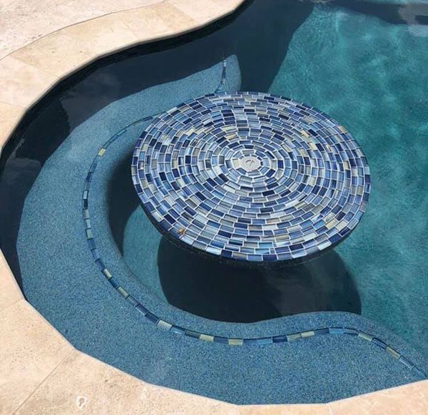 Round blue mosaic tile medallion set into the floor of a Houston pool