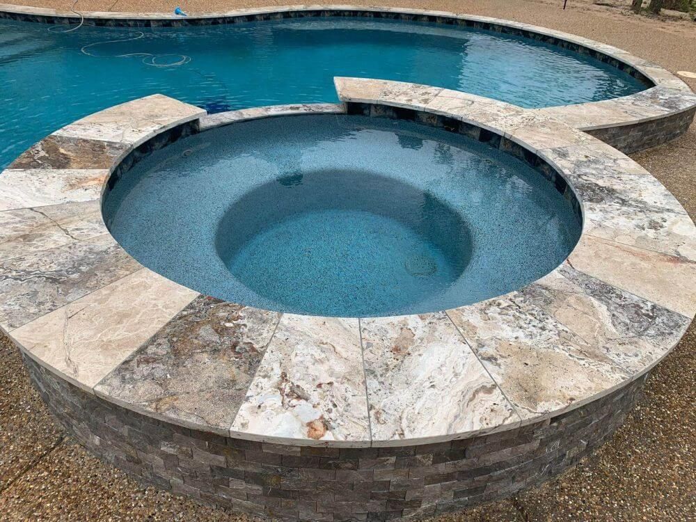 Finished travertine coping around a round Houston spa