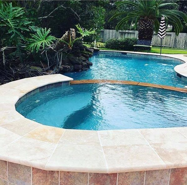 Freeform Houston pool with travertine decking and clear blue water