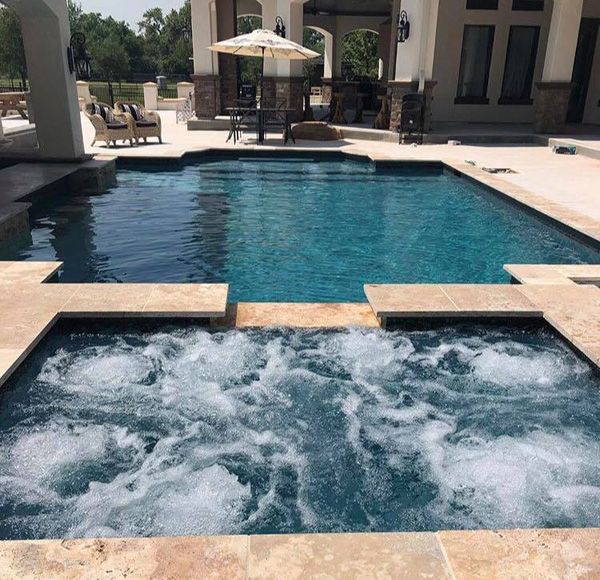 Built-in Houston spa with the jets running beside a dark tile pool