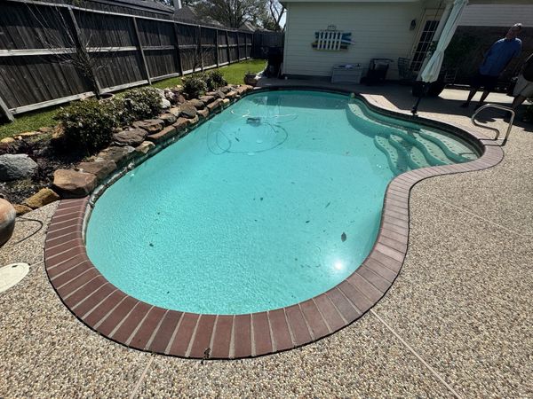 Dated red brick pool coping on an older Houston swimming pool