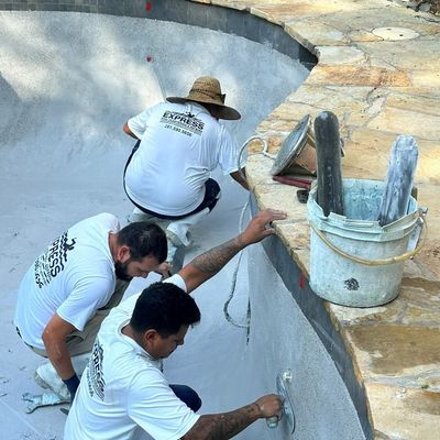 Three Express Pool Plastering crew members hand-troweling fresh plaster on a backyard pool in Kingwood, TX