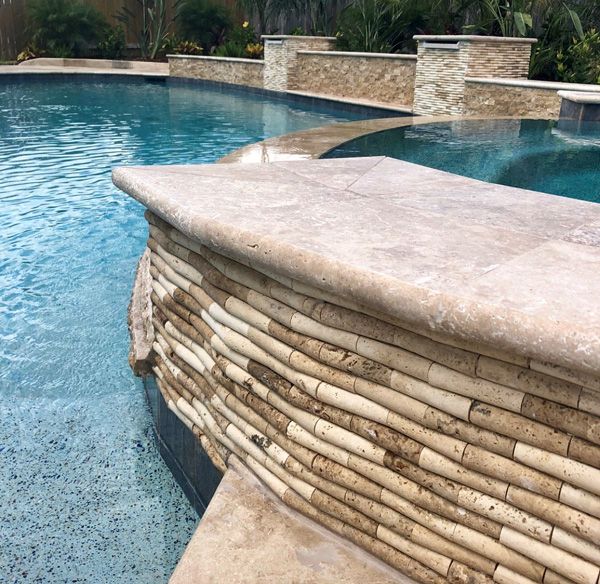 Raised Houston spa faced in stacked ledger stone with a spillway into the pool