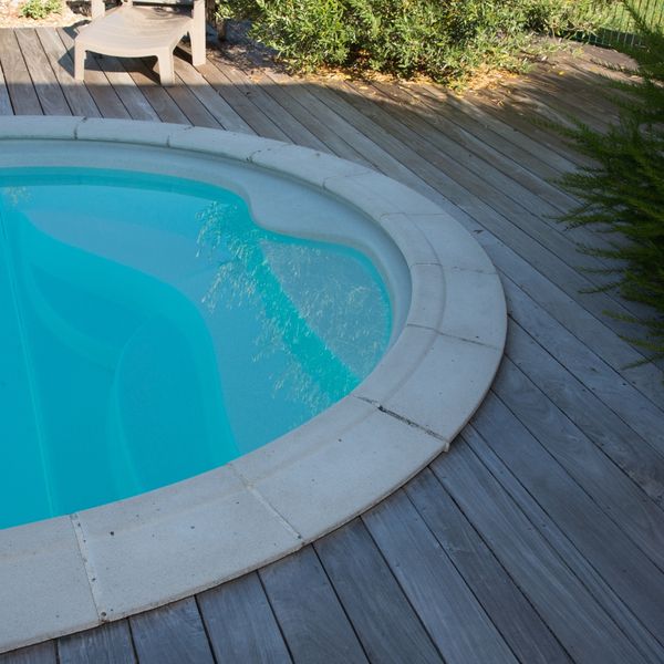 stone coping around a pool with a wood deck