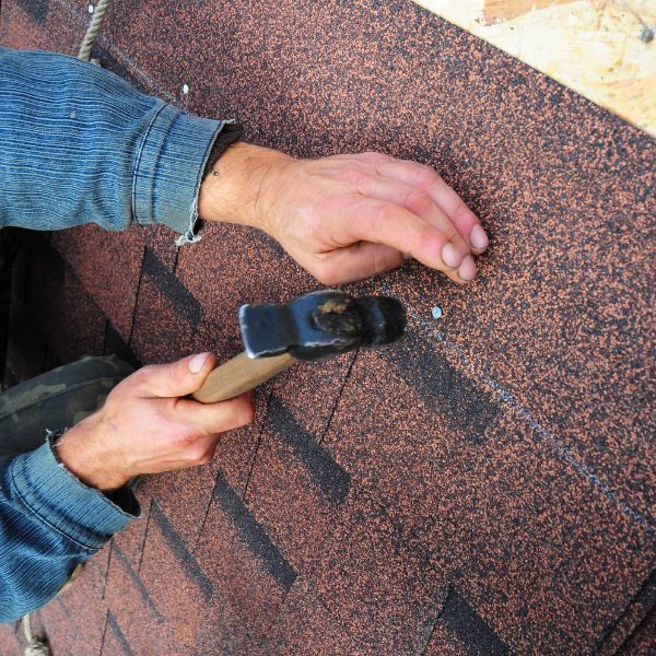 Hammering shingles on roof