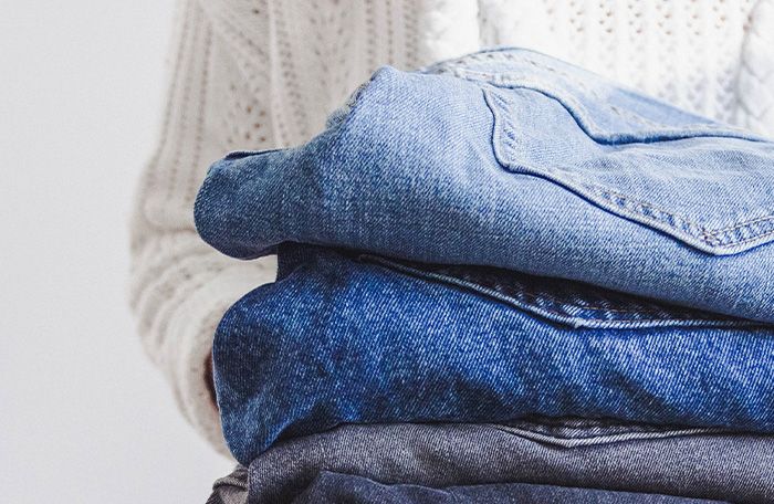 A woman holding a stack of jeans