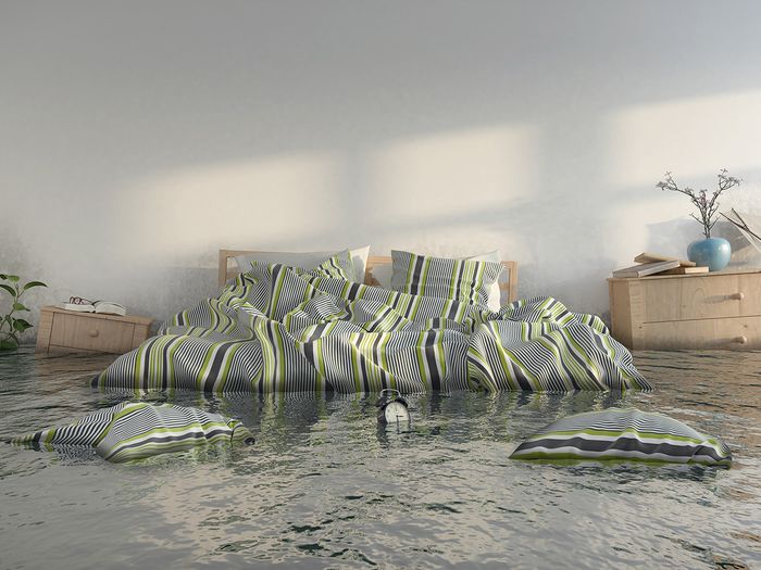 Flooded bedroom with high water line and floating furniture.