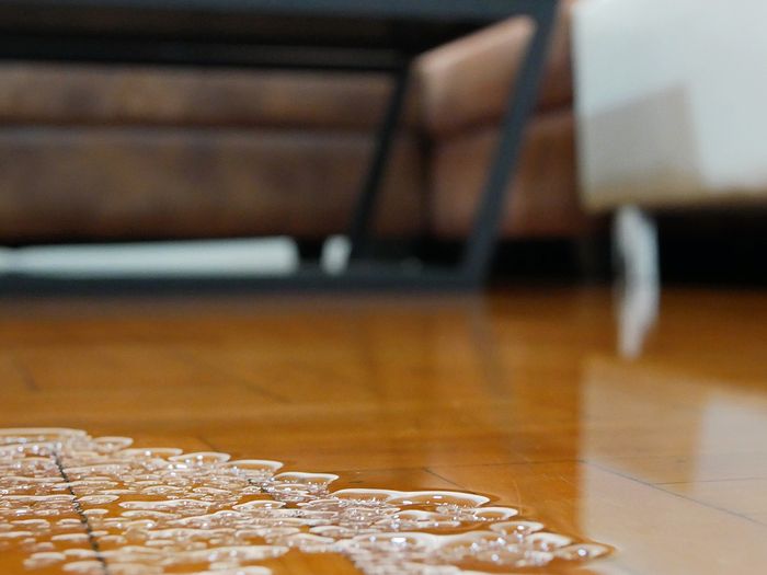 Close up of water flooding on living room parquet floor in a house - damage caused by water leakage