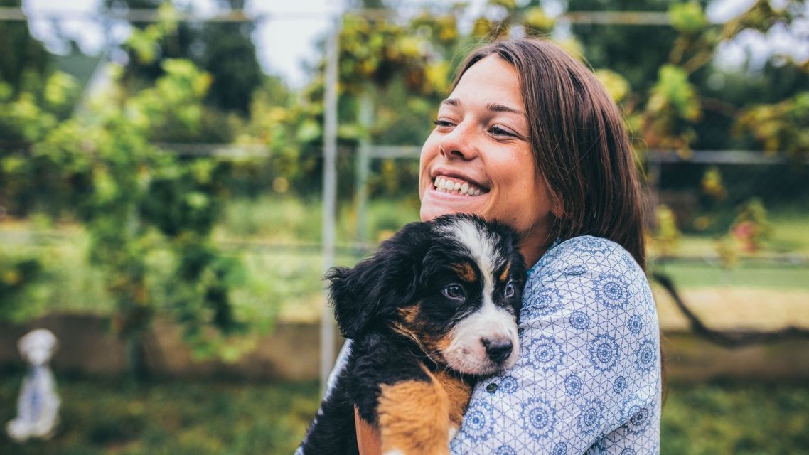 A young woman holding a puppy to her chest