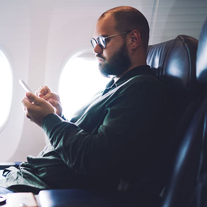 Man texting on a plane
