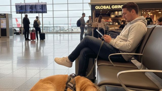 Man waiting at airport with his dog.