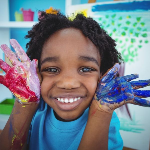 Child smiling with paint on their hands