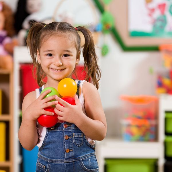 young girl in pig tails smiling while carrying plastic balls