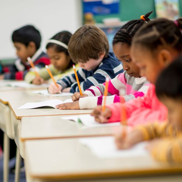 row of students sitting at desks and taking a test