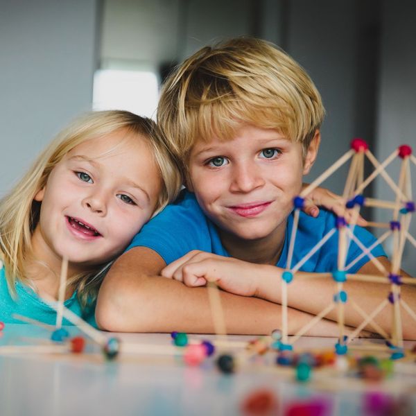 two young kids playing with toothpicks to build a bridge