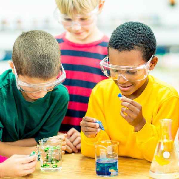 group of 3 students performing science experiments with beakers
