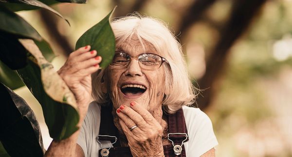 woman smiles next to plant 