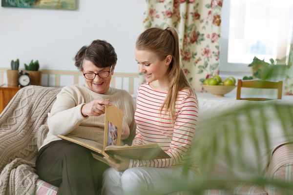 granddaughter looks at photo album with grandmother