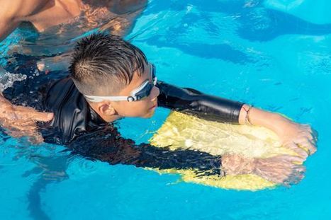 child using kickboard while instructor teaches them how to swim.jpg