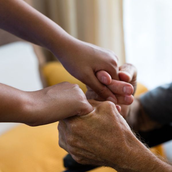 A nurse holding a patient's hands.