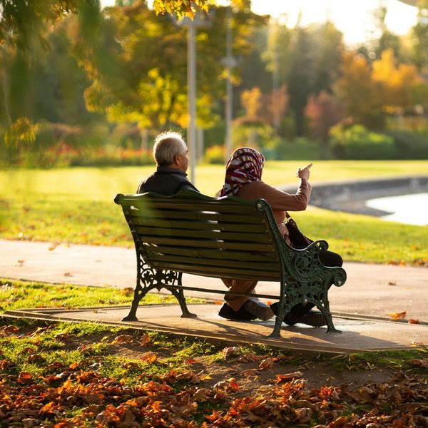 A senior couple sitting on a park bench during golden hour. 