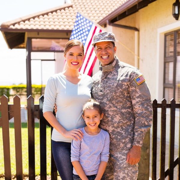 A military family smiling outside of their home