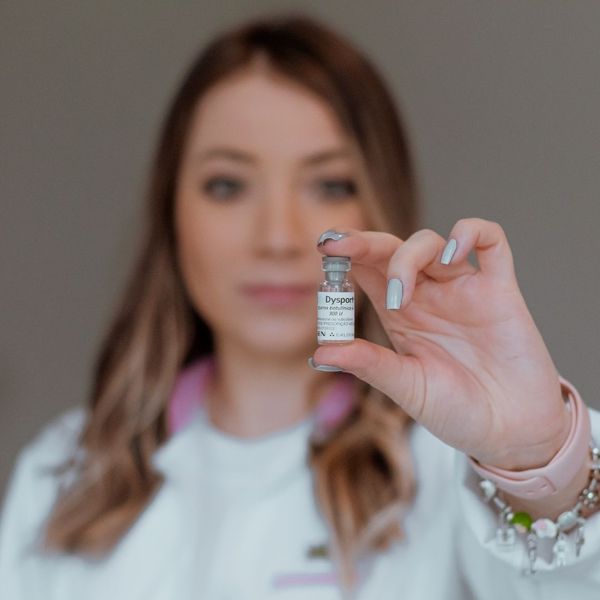 nurse injector holding up vial of filler