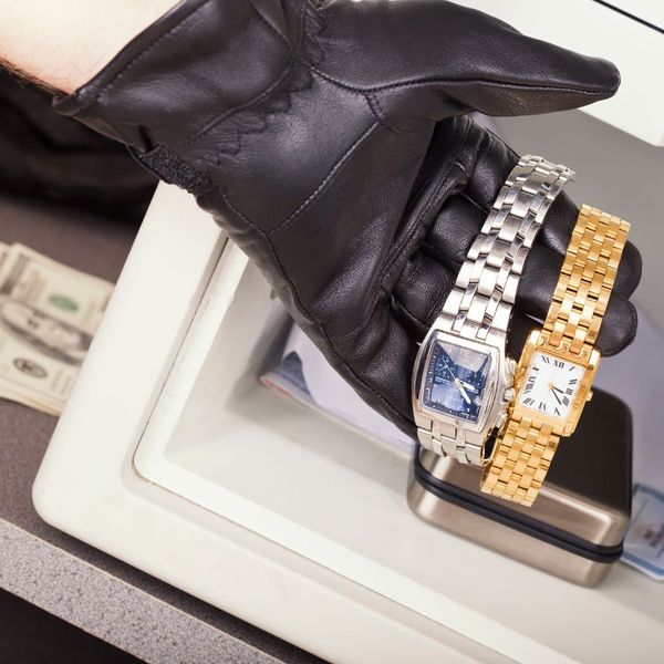 hand in black leather glove removing watches from a safe