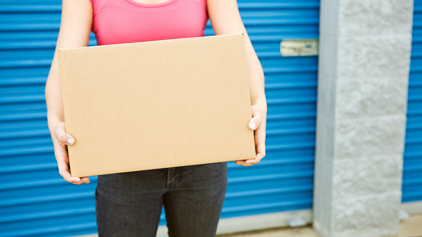 woman holding a box by a storage unit