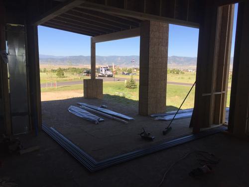 A construction photograph showing the wooden pre-frame and rough opening for a large sliding glass door system. The structure is built into a new home frame against a backdrop of Southern Utah's desert landscape, showing the precision required for high-end architectural glazing. Timber pre-frame for sliding glass wall